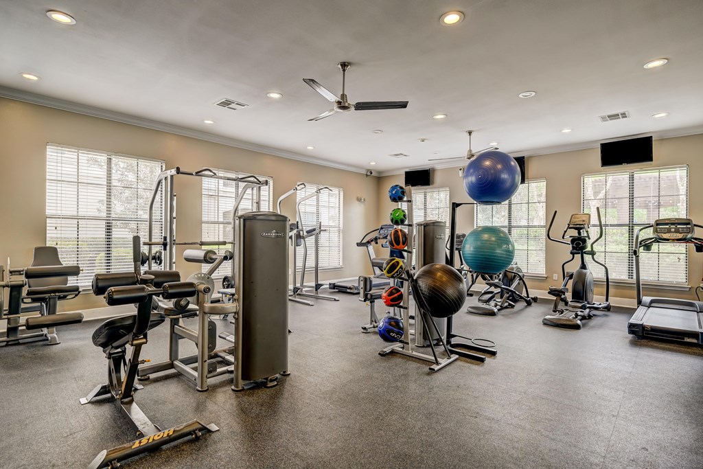 A spacious gym with a variety of equipment including a treadmill, elliptical machines, and a rowing machine.